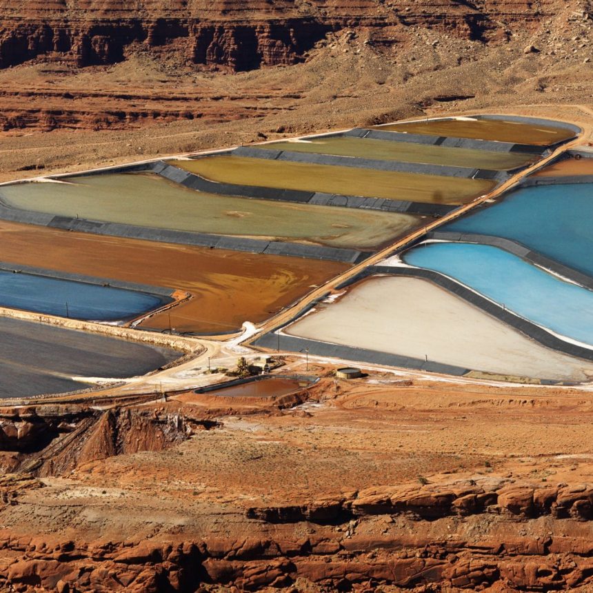 Aerial view of an arid, craggy landscape surrounding tailing ponds. Horizontal shot.